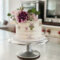 Hochzeitstorte Blumen Eine einstöckige Hochzeitstorte mit lila Blumen auf einer Etagere