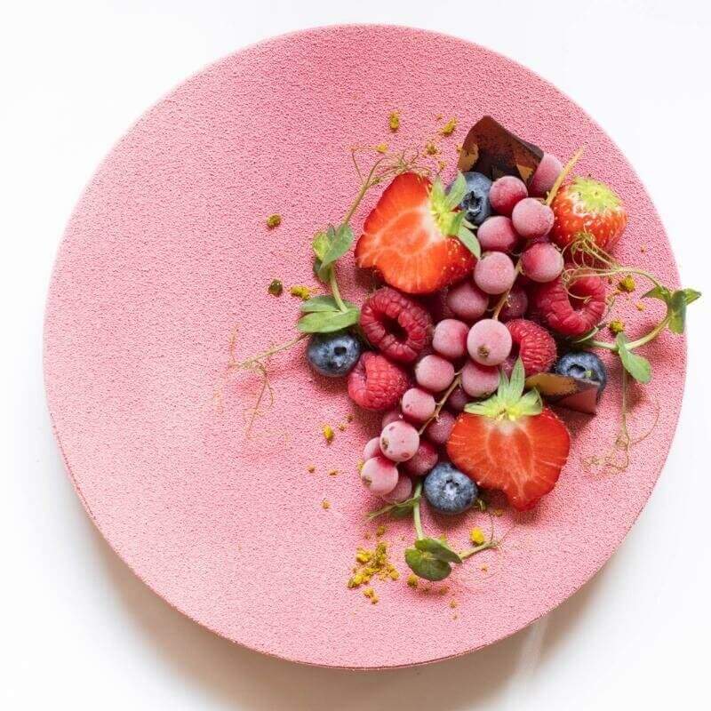 Eine rosa Torte aus Himbeermousse mit Beerendekor