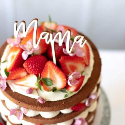 A cake from above with a wooden topper "Mama" and strawberries