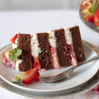 Ein Stück Torte mit Kakaoböden, weisser Creme und Erdbeeren