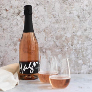 A bottle of rosé sparkling wine and two full champagne glasses