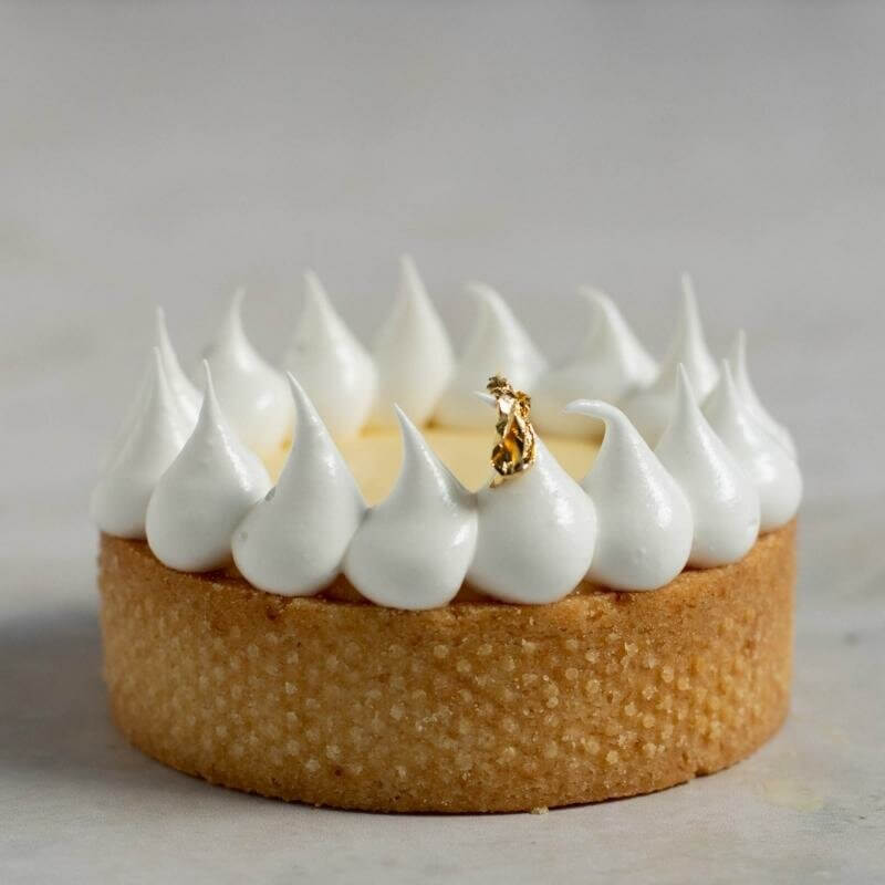 A citron tartelette with meringue topping on the edge and gold leaf as decoration