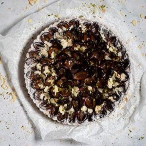 A plum tart with flaked almonds and icing sugar