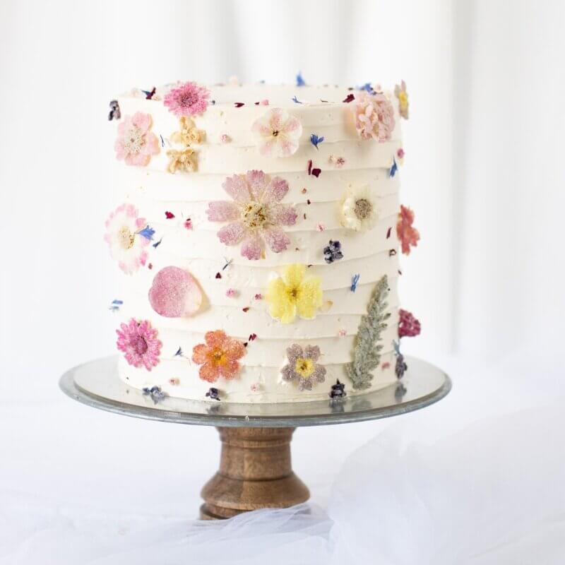 A cake decorated with cream and sugared flowers on etagere