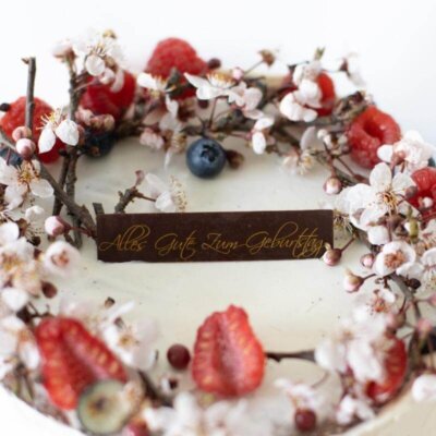 Ein Schokoladen-Rechteck mit Aufschrift Alles Gute zum Geburtstag auf einer Torte