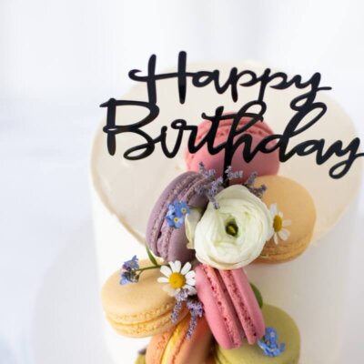 A cake decorated with macarons and flowers with caketopper