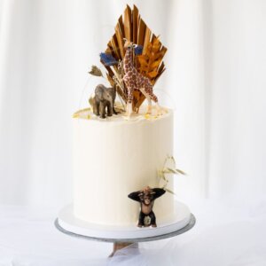 Birthday cake with dried flowers and animals. Giraffe, elephant and monkey on etagere.