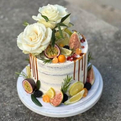 A single tier cake with visible layers. Decorated with fruits and flowers.