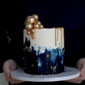 Cake with blue accents, golden drip and sprinkles