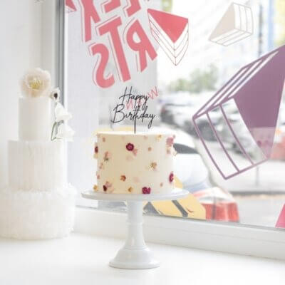 Eine Torte mit rosa Buttercreme Verzierung und Happy Birthday Topper