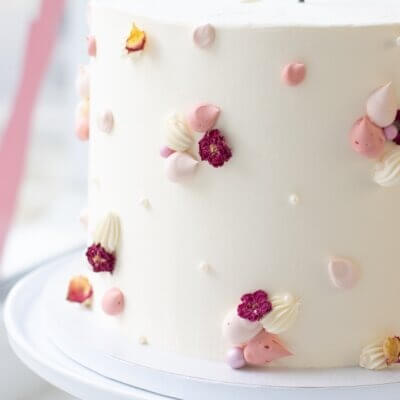 Eine Torte mit rosa Buttercreme Verzierung und Happy Birthday Topper